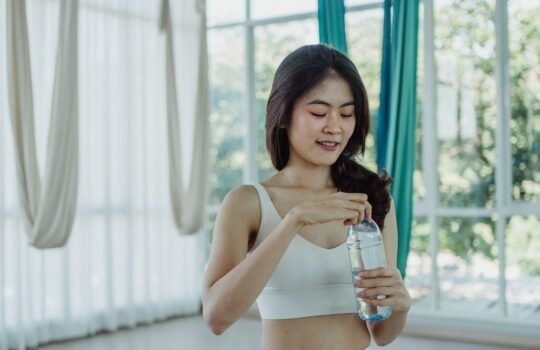 Phụ nữ uống nước hydration khi tập gym
